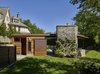 Modern home with Slope, Trees, Walkways, Hardscapes, Back Yard, Shrubs, Vertical Fences, Wall, Standard Layout Fireplace, Wood Burning Fireplace, Metal, Exterior, Sliding Door Type, and Outdoor. Entry to private spaces at rear of pool house. Photo 6 of Modern Pool House