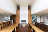 A central, double height, dual-sided fireplace anchors the home, connecting the main living spaces with the entrance and spacious gallery foyer on the opposite side. Photo 5 of Ravine House modern home