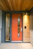 Mod-century modern inspired front door in a pop of orange against a two-toned grey exterior Photo 3 of The Sangar House modern home