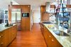 Modern home with Kitchen, Refrigerator, Cooktops, Range, Range Hood, Microwave, Dishwasher, Granite Counter, Wood Cabinet, Medium Hardwood Floor, Mosaic Tile Backsplashe, Ceiling Lighting, Pendant Lighting, Undermount Sink, and Concrete Floor. Kitchen Photo 5 of Home for Sale: Takoma Park House