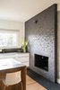 Modern home with Kitchen, Wood Cabinet, Engineered Quartz Counter, Medium Hardwood Floor, and Stone Slab Backsplashe. Kitchen fireplace. Original brick was damaged so it was painted dark grey. New slate hearth was added. High gloss Ikea lower cabinets are wrapped with custom white oak panels by AvenueTwo:Design. Photo 10 of Langley_Hawthorne Residence