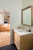 Modern home with Bath Room, Undermount Sink, Engineered Quartz Counter, Porcelain Tile Floor, and Wall Lighting. Guest Bathroom. Custom white oak vanity and matching mirror by AvenueTwo:Design. Caesarstone Blizzard top. All plumbing fixtures in the home are Kohler. Kitchen beyond. Photo 6 of Langley_Hawthorne Residence