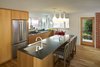 Modern home with Kitchen, Engineered Quartz Counter, Wood Cabinet, Medium Hardwood Floor, Stone Slab Backsplashe, Ceiling Lighting, Pendant Lighting, Refrigerator, Cooktops, and Undermount Sink. Kitchen was kept in the same area as the original one, and was kept modest in size which was appropriate for the house. New aluminum frame windows replaced the original steel. Door goes to outdoor covered dining area. Custom white oak cabinets by AvenueTwo:Design, countertops are Caesarstone. Matte white plumbing fixtures are Rubinet. Original brick exterior walls were uncovered and reconditioned. Photo 3 of Richthofen Residence