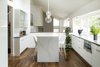 Modern home with Kitchen, Engineered Quartz Counter, Dark Hardwood Floor, Pendant Lighting, White Cabinet, and Microwave. Custom eat-in kitchen table. Solid Caesarstone waterfall fabricated by YK Stone. High gloss white cabinets by Vogo. Wide plank natural walnut flooring throughout. Photo 5 of Maplewood Residence