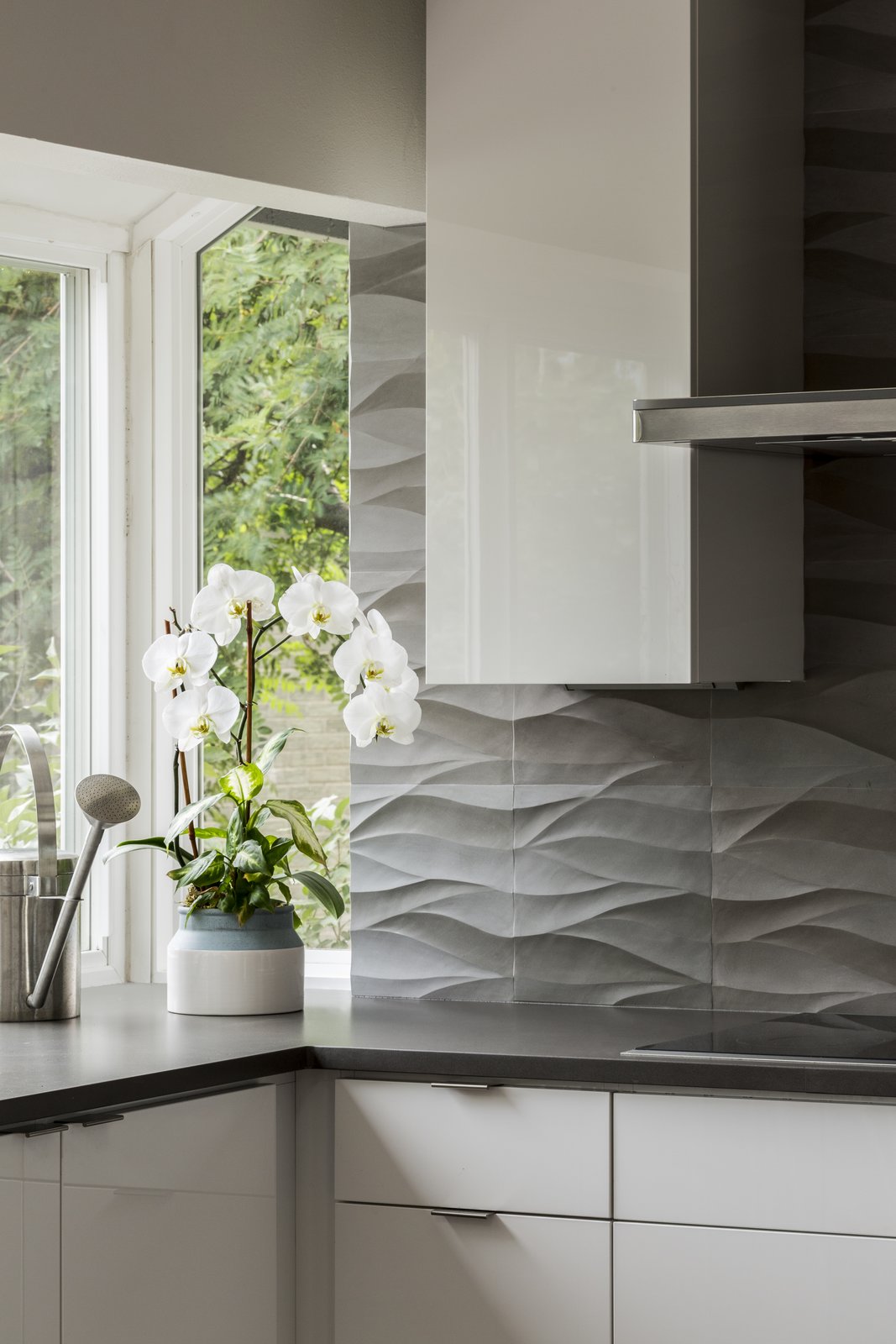 Detail of natural stone backsplash by Decorative Materials Inc. High gloss white cabinets by Vogo.