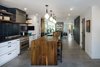 Modern home with Kitchen, Wood Counter, Pendant Lighting, Refrigerator, White Cabinet, Concrete Floor, Stone Tile Backsplashe, Range, and Undermount Sink. Kitchen with live edge walnut island slab Photo 6 of Lawrence Street Residence