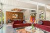 Modern home with Living Room, Rug Floor, Coffee Tables, Sectional, Porcelain Tile Floor, and Pendant Lighting. Looking into the dining room. The light over the table features hand blown glass pedals sitting on a glass shelf Photo 6 of Sunnyvale Eichler Remodel