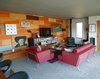 Modern home with Living Room, Chair, Sofa, End Tables, Bookcase, Ceiling Lighting, Recessed Lighting, Table Lighting, Coffee Tables, Accent Lighting, Medium Hardwood Floor, Carpet Floor, and Wood Burning Fireplace. Living Rm. / Great Rm. Photo 7 of Little Box on the Prairie