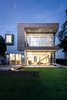 Modern home with Outdoor, Gardens, Decking Patio, Porch, Deck, Slope, Large Patio, Porch, Deck, Back Yard, Metal Fences, Wall, Metal Patio, Porch, Deck, Small Patio, Porch, Deck, Wood Patio, Porch, Deck, Walkways, Retaining Fences, Wall, Horizontal Fences, Wall, Grass, Landscape Lighting, Trees, Concrete Patio, Porch, Deck, Hardscapes, and Garden. West Elevation @ Dusk Photo of Spa Creek House