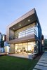 Modern home with Outdoor, Grass, Metal Patio, Porch, Deck, Side Yard, Metal Fences, Wall, Garden, Back Yard, Trees, Decking Patio, Porch, Deck, Wood Patio, Porch, Deck, Horizontal Fences, Wall, Small Patio, Porch, Deck, Slope, Hardscapes, Gardens, Large Patio, Porch, Deck, Concrete Patio, Porch, Deck, Field, Landscape Lighting, and Walkways. View from Southwest @ Dusk Photo 2 of Spa Creek House