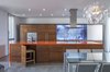 Modern home with Kitchen, Wood Cabinet, Refrigerator, Undermount Sink, Microwave, Range Hood, Recessed Lighting, Wall Oven, Quartzite Counter, Concrete Floor, and Cooktops. Colors from dramatic, Icelandic landscapes inspired the contrasting interiors. Volcanic orange creates a multifunctional gathering point at the heart of the home while the swimming pool brings in a lagoon hue; the cabinets recall glaciers and lava. In the kitchen, "disappearing" chairs are stored under the island to maximize space. Photo 4 of Dawnsknoll