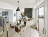 Modern home with Engineered Quartz Counter, Colorful Cabinet, Wood Cabinet, Light Hardwood Floor, Ceiling Lighting, Refrigerator, Chair, Sofa, Dining Room, Table, and Accent Lighting. Airy one room living/dining, with multiple sliding doors opening to a deck. Photo 2 of The Lighthouse