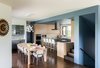 The interior palette echoes the simple use of materials with walnut floors, oak and grey cabinets. Restraint is contrasted with whimsy, however with unexpected pops of bold color throughout the home: a blue ceiling and walls wrap around the kitchen and centrally located stair articulating the service side of the home. Photo 3 of Sunset House modern home