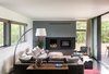Modern open concept living room in Boulder with a fireplace, gray and white walls, wood floors. Large slider opens to backyard. Photo of Sunset House modern home
