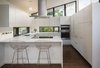 Modern home with Kitchen, Range Hood, and Cooktops. Without increasing the size of the kitchen, we reworked the space to create a family friendly design. This was accomplished by moving the range to the island, adding counter seating and increasing storage with full height cabinetry. Natural lighting in the kitchen was improved by adding low counter height windows. Photo 5 of Mid Century Re-Modern