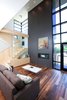 Modern home with Wood Tread, Glass Railing, Medium Hardwood Floor, Gas Burning Fireplace, Windows, Ribbon Fireplace, Metal, and Picture Window Type. Key to the interior design is the incorporation of natural ash wood elements. These are used on the loft railing, featured cabinetry and showcased on the vertical staircase. The ash kitchen/ dining ceiling bulkhead completes the idea of linear circulation. The terminus on axis with the ash linear bulkhead is the living room fireplace, incorporated in the chimney form which reinforces its street presence. Photo 5 of City Cottage