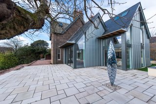 In 2016, Hyve Architects completed the renovation of The Gables, a heritage home in Stonehaven. A modern extension features an open kitchen and family room that connects to the main stone home. The double-pitched roofline of the new structure references the end gable line of the original house.