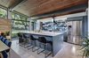 Modern home with Kitchen, Wood Cabinet, Range Hood, Refrigerator, Dishwasher, Recessed Lighting, Range, Cooktops, Concrete Floor, Ice Maker, Colorful Cabinet, Undermount Sink, Ceramic Tile Backsplashe, and Engineered Quartz Counter. The natural material palette of stone, wood, and polished concrete is enhanced by views of the surrounding greenery. Photo 6 of Re-Open House