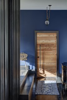 The entry sequence starts with a humble and compressed space that expands upon entry. The front door is made of repurposed wood. 