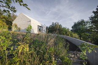 The approach to the home is defined by a concrete wall and a gravel path.