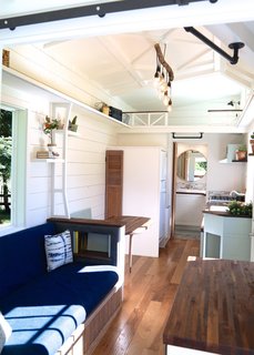 The use of light colors on the walls and ceiling of The Pacific Pioneer by Handcrafted Movement keeps the two lofted sleeping spaces at either end of the tiny home from feeling claustrophobic, while the blues, greens, and natural wood of the furniture and cabinetry are simple but thoughtful.