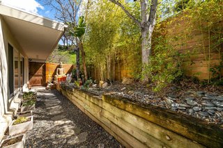 The side yard features a Zen garden with local plantings, and an area that is partially covered by a cantilevering roof.