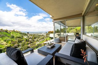 A glass guardrail on the outdoor terrace provides uninterrupted views of the valley below.