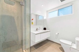 The updated bathrooms are clean, simple, and predominantly white, with heated floors and oversized showerheads.