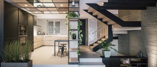 The kitchen opens directly into the living room. The staircase leading to the bedrooms on the second floor continues the same material palette.