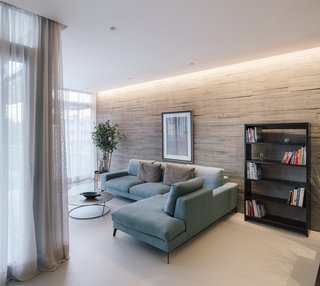 The home’s furniture and window treatments complement the neutral tones of the exterior and interior materials. Textured walls of board-formed concrete provide visual interest in the living room.