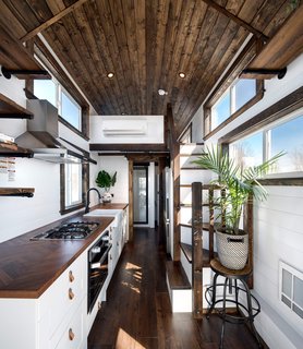 The interior reveals a well-lit, warm, and cozy space that is largely dominated by the full-size kitchen, although there is still space for a full bath in the back and a full-sized sofa that can open into to a guest bed.