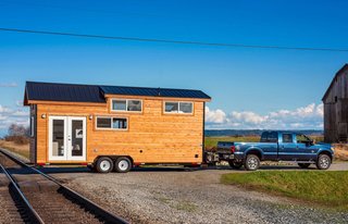 The exterior is clad in cedar siding with metal roofing; the complex roof form accommodates the lofted spaces inside.