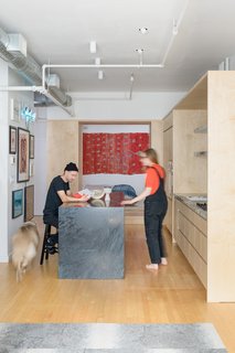 The open, 920-square-foot loft felt right to homeowners and creative couple Aubrey Ament and Will Glaser, but they needed to separate public and private spaces. A thick wall of storage did the trick.