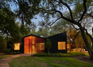 The exterior is clad in board-and-batten siding, while the front porch is covered with stained pine. Both materials have a vertical emphasis, which speaks to the heritage oak trees on the .75-acre property.