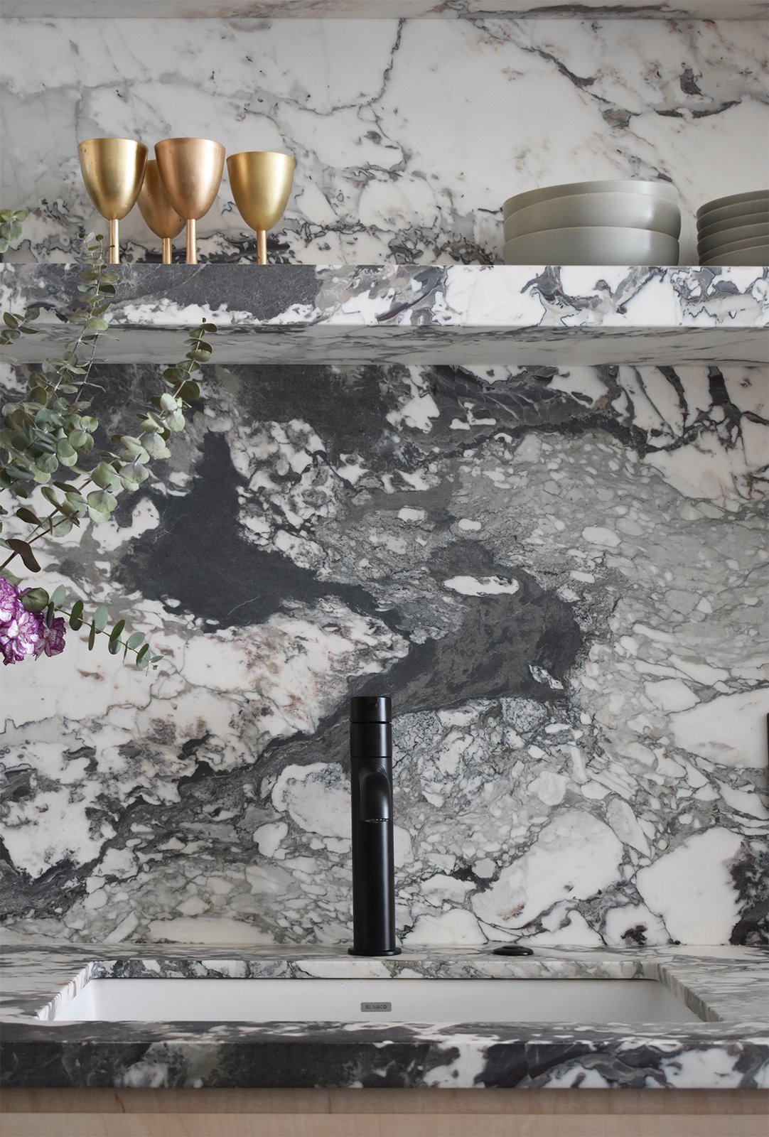Dean selected a black faucet and a white sink bowl rather than a more typical metallic finish so that both would blend better with the active veining of the black and white marble.