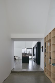 High ceilings, white walls, and a polished concrete floor create a simple backdrop for the black-and-wood finishes of the kitchen.