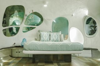 Openings along the back wall of the bedroom provide glimpses of the tiled bathroom.