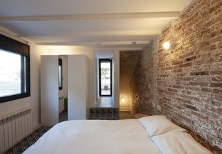 The bedrooms receive light from windows that have been punched out of the masonry and overlook the outdoor patio below.