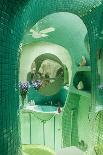 The small size of the teal mosaic tile allows it to hug the curves of the bathroom's walls, ceiling, and built-in shelving.