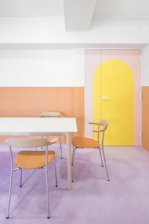 The pastel tangerine chairs in the dining area pick up the orange wainscotting of the walls, and the simple lines of the dining furniture allow the walls and finishes to function as artwork.