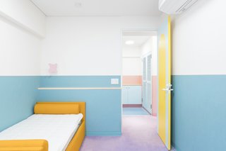 Each bedroom has colored wainscotting but is otherwise minimally furnished, aside from a boldly colored bed and other simple furniture.