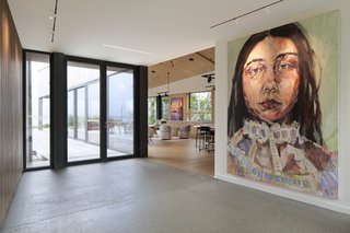 An oversized piece of artwork greets visitors once they step into the glazed entry vestibule, with the living room and deck beyond. The wide opening and lack of doors between the vestibule and the "living" volume of the two shed-like structures allows not only for ease of movement and sightlines, but for light and air to travel through the spaces.