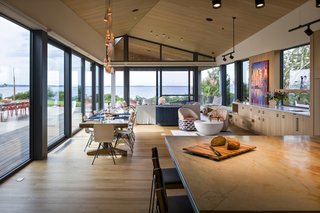 Floor-to-ceiling glazing allows guests to look from the kitchen island into the open living and dining area, and to the ocean views in the distance.