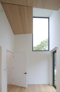 Simple finishes in one of the guest rooms is offset by the views of the outdoors. A a clerestory window lets in light above, and an operable window/door with a shade allows for easy visual and physical access to the landscape.