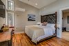 Modern home with Bedroom, Bed, Ceiling Lighting, Recessed Lighting, Medium Hardwood Floor, and Night Stands. Interior of efficiency cabin. The headboard and bed frame were created from reclaimed barn wood sourced locally. Windows were strategically placed to frame trees and the forest. Every cabin is furnished with custom artwork, photography, and furniture created by local artisans from Transylvania County, NC. Photo 7 of Pilot Cove : Forest Lodging