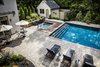 Resting to the side of the pool is the pool house which was constructed to look like the existing house with matching shingles and stucco finish. The custom fire features to the side of the pool house fence add a beautiful charm along with the surrounding landscaping and landscape lighting. Photo 6 of The Kalimtzis Residence modern home
