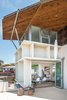 The main dining area's accordion door opens up to the balcony with an ocean view and salty breeze. Above the dining space sits the 3rd story home office with 180 degree views. Photo of The Beach House modern home