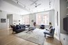 Modern home with Living Room, Chair, Light Hardwood Floor, Ceiling Lighting, Sofa, and Coffee Tables. Large living room with beautiful exposures, hardwood floors, and natural light. Photo of Stunning at Every Angle in Tribeca