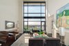 Modern home with Living Room, Wood Burning Fireplace, Bench, Chair, Floor Lighting, and Sofa. A double height floor-to-ceiling window allows light to pour in through the living room and offers magnificent views of the East River Photo of NYC Duplex with Water Views in Peter Marino-Designed Condo