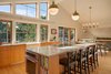 Modern home with Kitchen, Wall Oven, Cooktops, Light Hardwood Floor, Pendant Lighting, Wood Cabinet, and Drop In Sink. The renovation of this midcentury home in Falmouth, Maine, incorporates a modern aesthetic while preserving the home's midcentury character, as well as making it more energy efficient. Now, the bright and spacious kitchen opens to the dining and living spaces. The additional row of windows follows the roofline and fills the space with natural light. Photo 3 of Midcentury Makeover